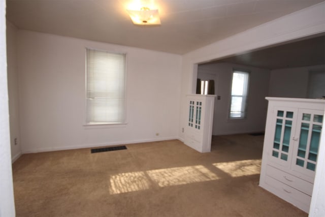 carpeted empty room with visible vents and baseboards