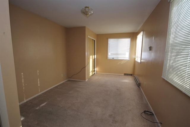 carpeted spare room with a baseboard heating unit