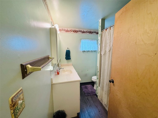 bathroom with toilet, vanity, and hardwood / wood-style floors