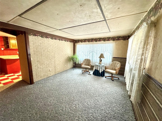 sitting room featuring carpet floors and brick wall