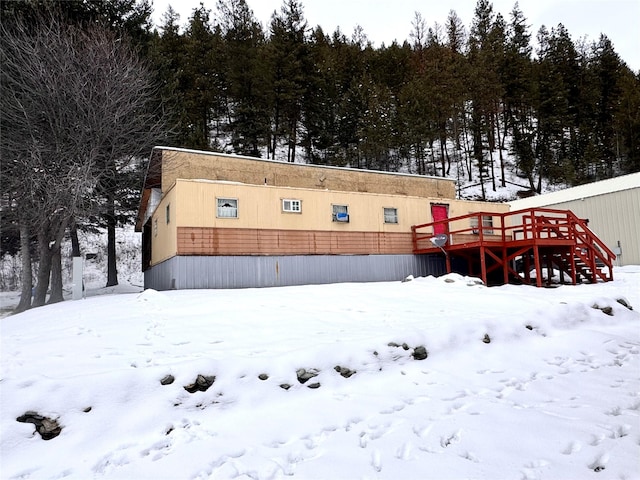 snow covered back of property featuring a wooden deck