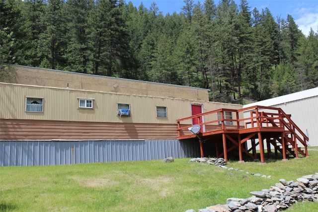 back of property featuring a wooden deck and a lawn