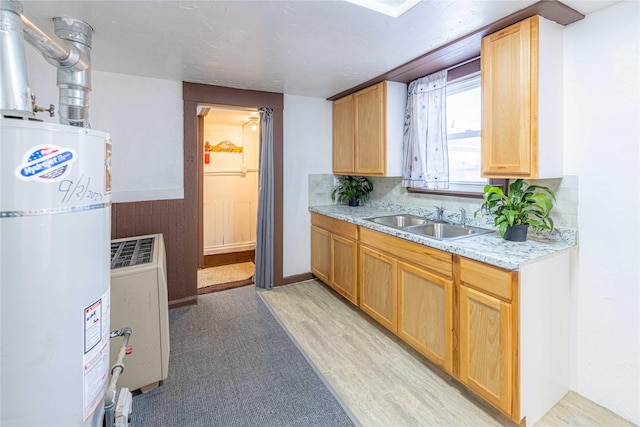 kitchen with light stone counters, sink, and secured water heater