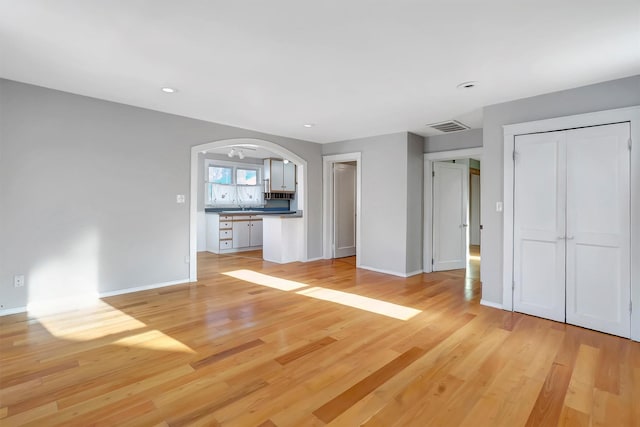 unfurnished living room with sink and light wood-type flooring