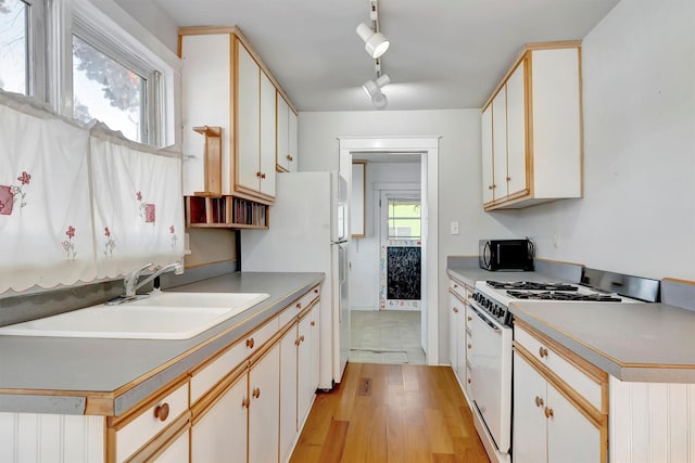 kitchen featuring light wood-type flooring, white cabinetry, sink, and white appliances