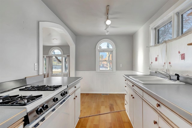 kitchen featuring sink, white cabinetry, white range with gas cooktop, light wood-type flooring, and rail lighting