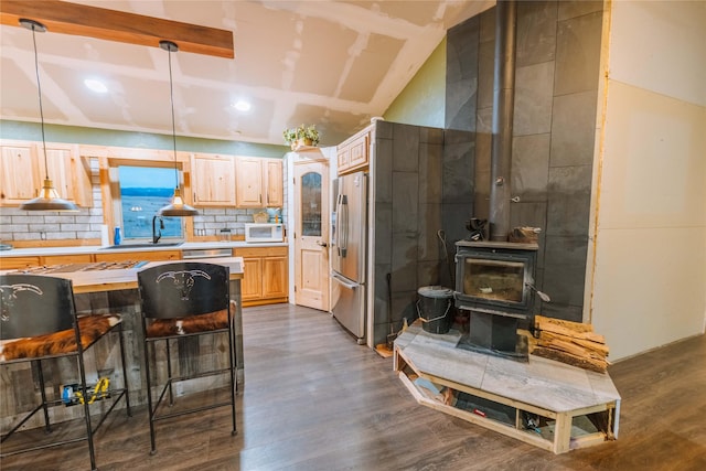 kitchen with white microwave, light countertops, stainless steel fridge with ice dispenser, light brown cabinetry, and decorative light fixtures