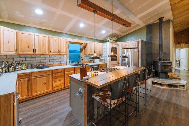 kitchen with decorative light fixtures, stainless steel appliances, dark wood-type flooring, a breakfast bar, and a wood stove