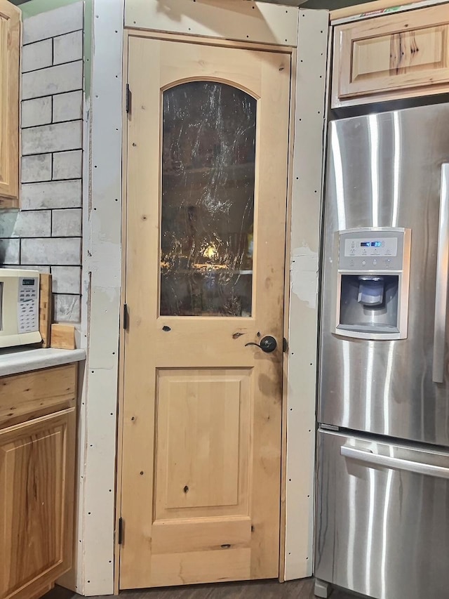 kitchen featuring light countertops, light brown cabinetry, and stainless steel fridge with ice dispenser