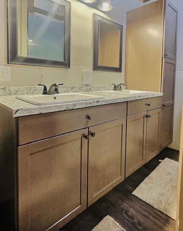 bathroom featuring double vanity, wood finished floors, and a sink