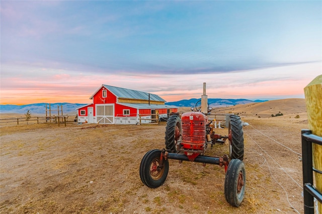 exterior space featuring a mountain view, a barn, an outdoor structure, and fence