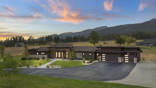 view of front of home featuring a garage, a mountain view, and a lawn