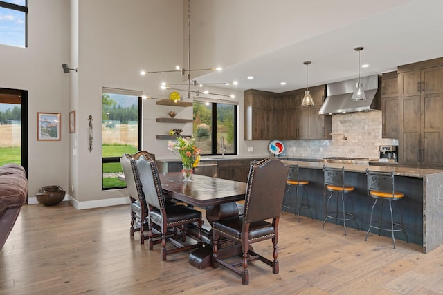 dining space with plenty of natural light, a high ceiling, and light hardwood / wood-style floors