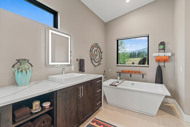 bathroom with a tub to relax in, vanity, vaulted ceiling, and a wealth of natural light