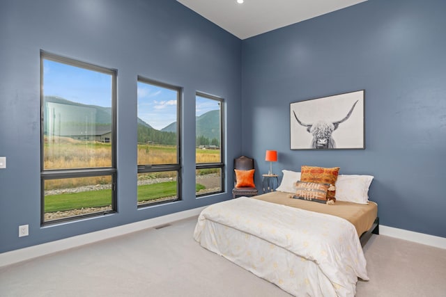 bedroom featuring carpet, a mountain view, and multiple windows