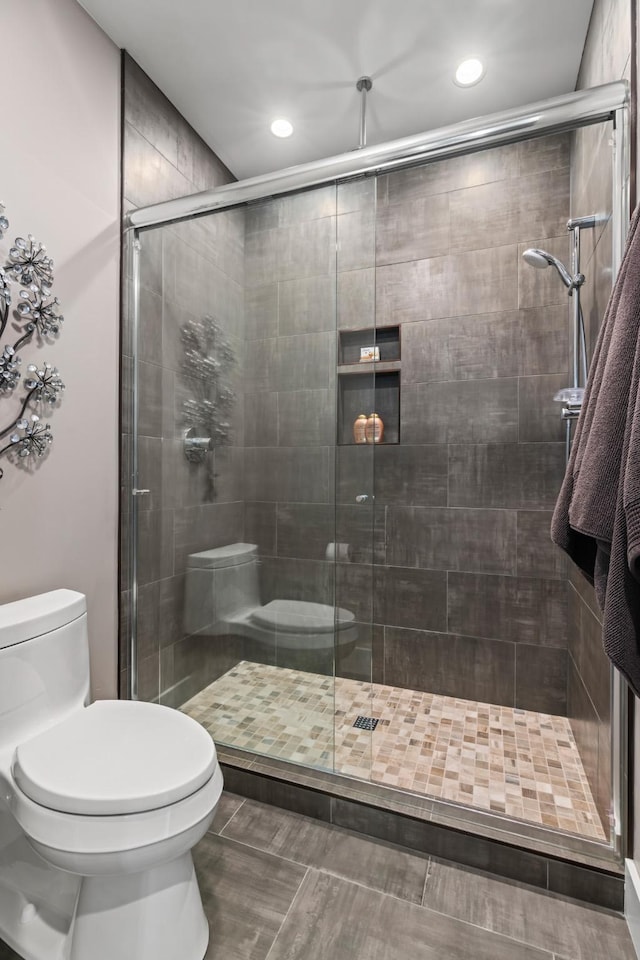 bathroom featuring toilet and a shower with door