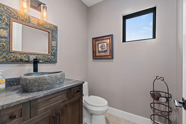 bathroom with toilet, vanity, and tile patterned flooring