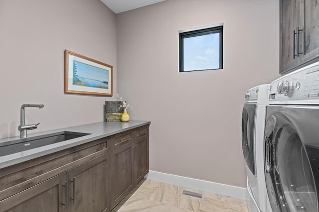 washroom with washing machine and dryer, cabinets, and sink