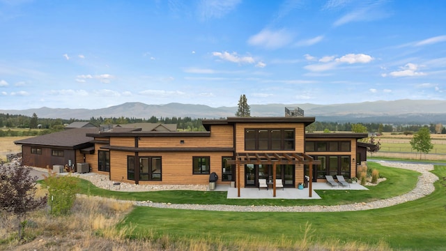 back of house featuring cooling unit, a mountain view, a lawn, and a patio