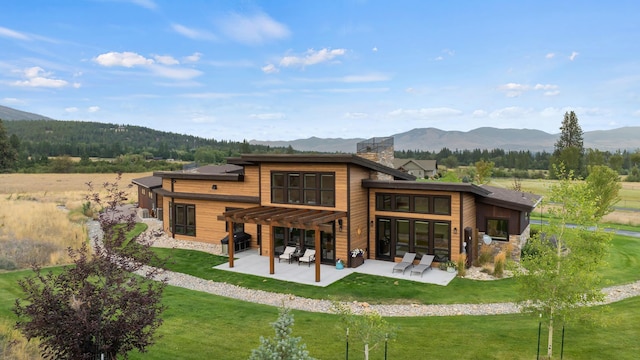 back of property with a lawn, a pergola, a mountain view, and a patio