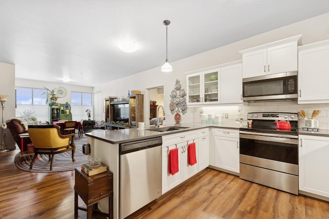 kitchen with sink, appliances with stainless steel finishes, white cabinets, decorative light fixtures, and kitchen peninsula