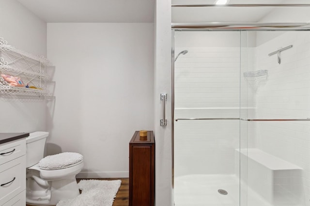 bathroom featuring vanity, wood-type flooring, a shower with door, and toilet