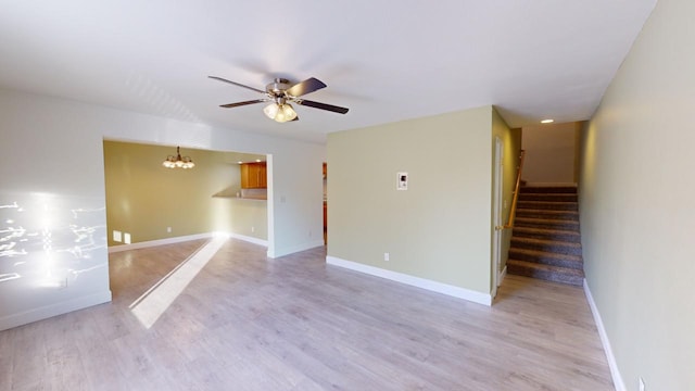 unfurnished room featuring light wood-type flooring and ceiling fan with notable chandelier