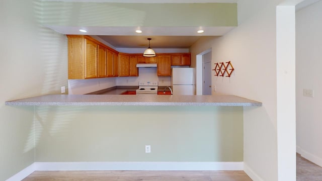 kitchen with light hardwood / wood-style floors, white appliances, kitchen peninsula, and hanging light fixtures