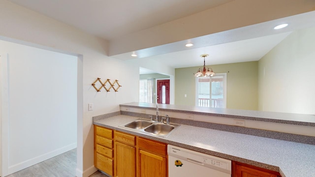 kitchen with dishwasher, decorative light fixtures, an inviting chandelier, sink, and light hardwood / wood-style flooring