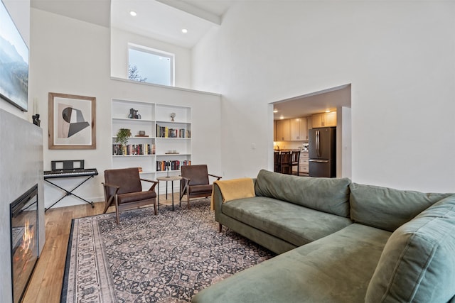 living room featuring high vaulted ceiling, built in features, beamed ceiling, and hardwood / wood-style flooring