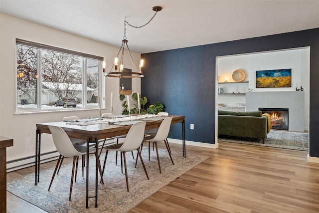 dining area with baseboard heating, a notable chandelier, and light hardwood / wood-style floors