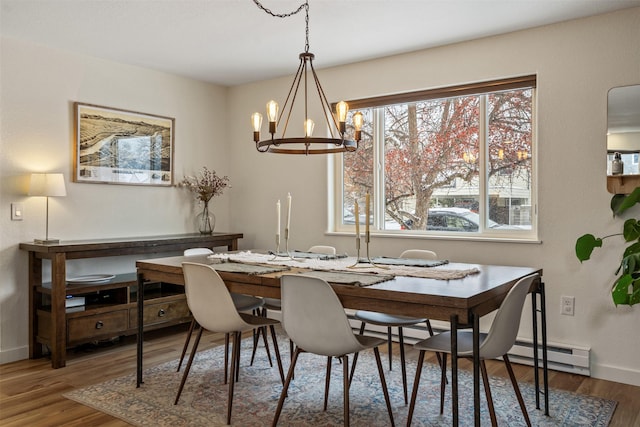 dining space with wood-type flooring, a chandelier, and a baseboard heating unit