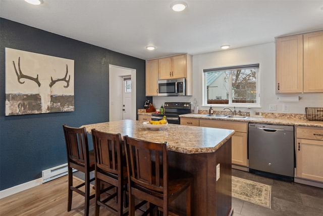 kitchen with a kitchen breakfast bar, stainless steel appliances, light brown cabinetry, and sink