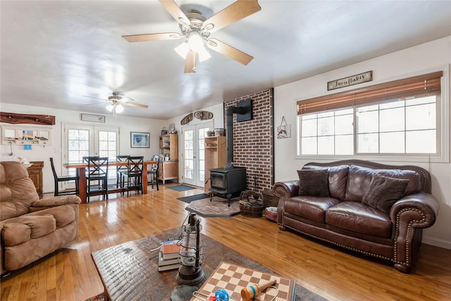 living room featuring ceiling fan, wood-type flooring, french doors, and a wood stove