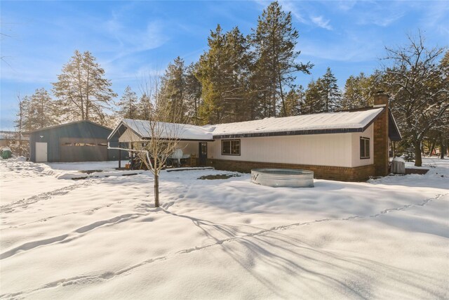 snow covered back of property featuring a hot tub