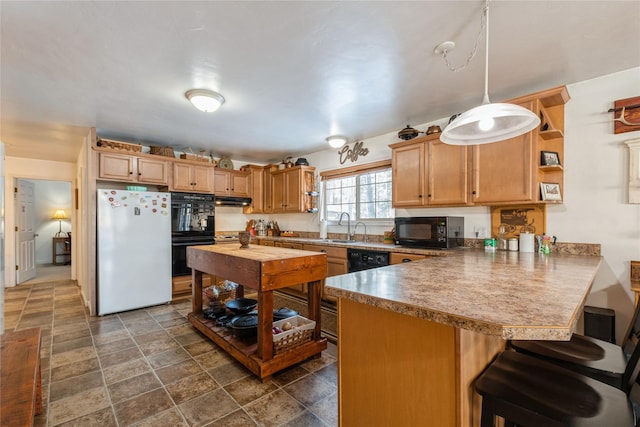 kitchen featuring kitchen peninsula, decorative light fixtures, black appliances, a breakfast bar, and sink