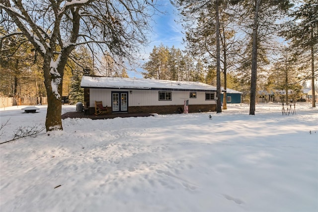 snow covered house with french doors and brick siding