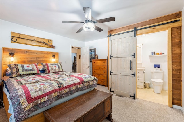 carpeted bedroom featuring ceiling fan, a barn door, and connected bathroom