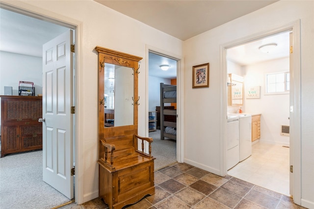 hall featuring washing machine and dryer, baseboards, and carpet