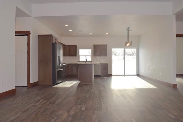 kitchen with decorative light fixtures, a kitchen island, sink, appliances with stainless steel finishes, and dark wood-type flooring