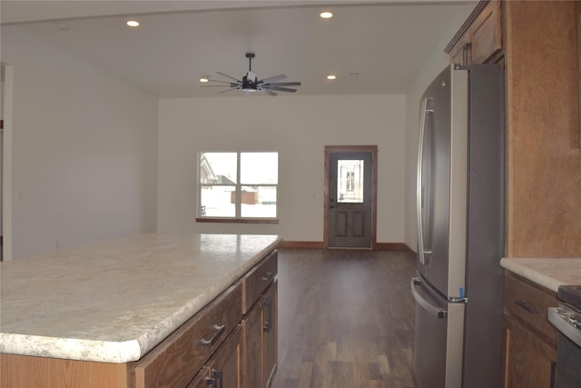 kitchen with ceiling fan, dark hardwood / wood-style floors, stainless steel appliances, and a center island