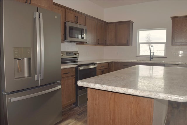 kitchen with sink, appliances with stainless steel finishes, dark hardwood / wood-style floors, and a kitchen island