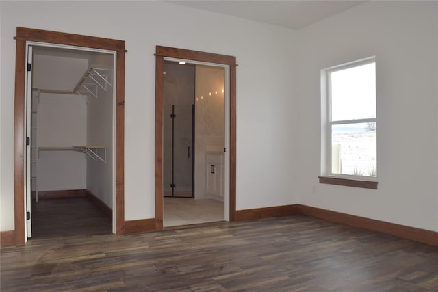 unfurnished bedroom with ensuite bath, dark hardwood / wood-style flooring, and a walk in closet