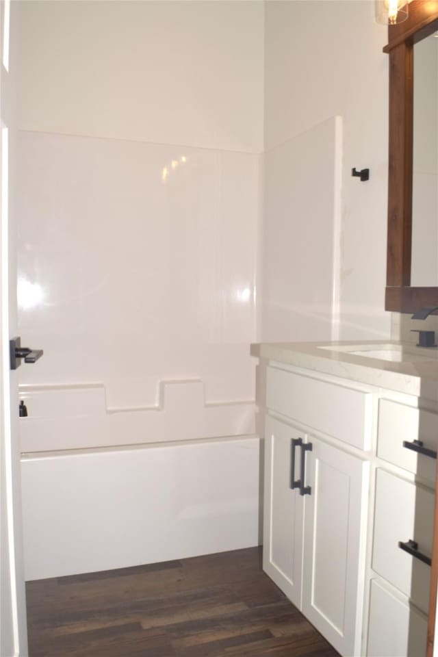 bathroom featuring wood-type flooring, vanity, and bathing tub / shower combination