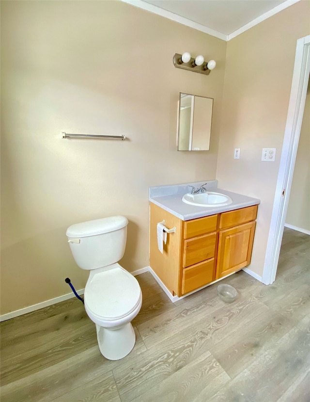 bathroom with wood-type flooring, toilet, vanity, and crown molding