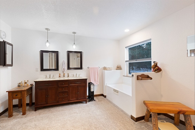 bathroom featuring a tub to relax in, vanity, and a textured ceiling