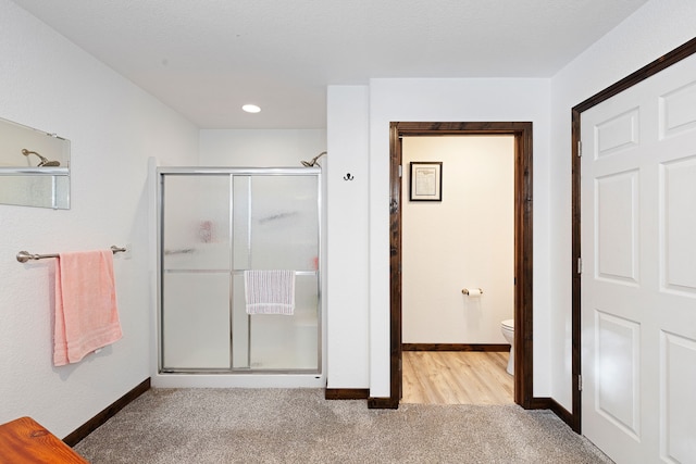 bathroom with a shower with shower door and toilet