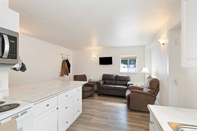 kitchen featuring light wood-type flooring, white cabinets, and electric stove