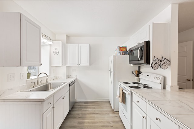 kitchen with stainless steel appliances, light hardwood / wood-style flooring, white cabinetry, and sink