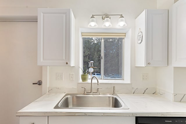 kitchen with light stone countertops, black dishwasher, white cabinets, and sink